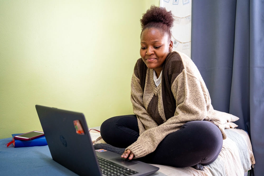 A Zambian student studying on her bed